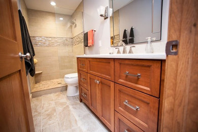 Mid-sized trendy beige tile and ceramic tile porcelain tile doorless shower photo in Milwaukee with flat-panel cabinets, medium tone wood cabinets, a one-piece toilet, gray walls, an undermount sink and quartzite countertops