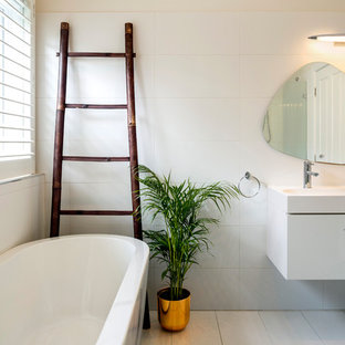 Inspiration for a contemporary bathroom in Melbourne with flat-panel cabinets, white cabinets, a freestanding tub, ceramic tile, white walls, ceramic floors, an integrated sink, grey floor, white benchtops and white tile.