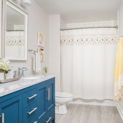 Large elegant kids' white tile and porcelain tile porcelain tile and gray floor bathroom photo in Charlotte with shaker cabinets, blue cabinets, a two-piece toilet, gray walls, an undermount sink, marble countertops and gray countertops