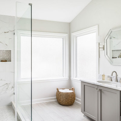Large elegant master white tile and porcelain tile porcelain tile and beige floor corner shower photo in Charlotte with shaker cabinets, gray cabinets, a two-piece toilet, white walls, an undermount sink, marble countertops, a hinged shower door and gray countertops