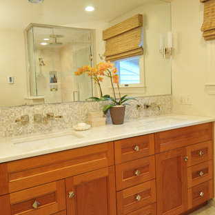 Idee per una stanza da bagno padronale classica di medie dimensioni con ante con riquadro incassato, ante in legno scuro, doccia ad angolo, piastrelle beige, piastrelle di vetro, pareti beige, lavabo sottopiano, top in marmo, porta doccia a battente, pavimento in gres porcellanato, pavimento grigio e top bianco