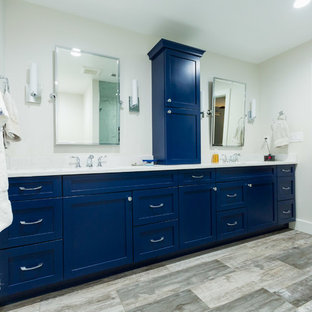 Photo of a large transitional master bathroom in DC Metro with shaker cabinets, an alcove tub, a two-piece toilet, beige walls, an undermount sink, a corner shower, plywood floors, brown floor, a hinged shower door, blue cabinets, white tile, marble, marble benchtops and white benchtops.