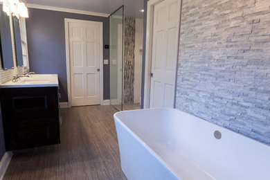 Пример оригинального дизайна: большая главная ванная комната в стиле неоклассика (современная классика) с врезной раковиной, фасадами с утопленной филенкой, темными деревянными фасадами, столешницей из искусственного кварца, отдельно стоящей ванной, душем без бортиков, инсталляцией, белой плиткой, керамогранитной плиткой, фиолетовыми стенами и полом из керамогранита