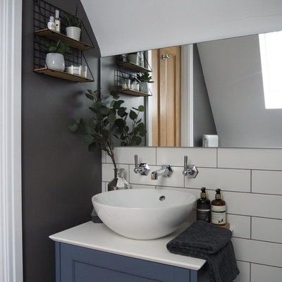 Alcove shower - small scandinavian master white tile and ceramic tile ceramic tile and gray floor alcove shower idea in West Midlands with shaker cabinets, blue cabinets, a wall-mount toilet, gray walls, quartz countertops, a hinged shower door and white countertops