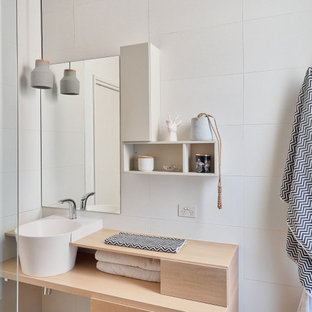 Photo of a mid-sized scandinavian bathroom in Melbourne with furniture-like cabinets, light wood cabinets, a freestanding tub, a corner shower, black tile, grey walls, grey floor, an open shower, grey benchtops, a single vanity and a built-in vanity.