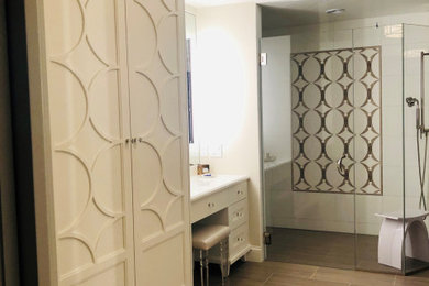 Идея дизайна: большая главная ванная комната в стиле неоклассика (современная классика) с фасадами островного типа, белыми фасадами, отдельно стоящей ванной, душем без бортиков, белой плиткой, стеклянной плиткой, серыми стенами, полом из керамической плитки, врезной раковиной, стеклянной столешницей, серым полом, душем с распашными дверями, белой столешницей, нишей, тумбой под две раковины и встроенной тумбой
