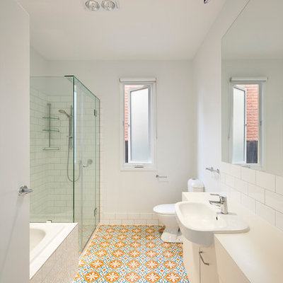 Inspiration for a mid-sized contemporary white tile and subway tile ceramic tile and multicolored floor bathroom remodel in Melbourne with flat-panel cabinets, white cabinets, a one-piece toilet, white walls, a drop-in sink, laminate countertops, a hinged shower door and white countertops