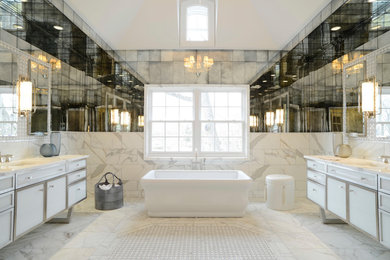 Photo of a large modern ensuite bathroom in New York with glass-front cabinets, white cabinets, a freestanding bath, white tiles, marble tiles, marble flooring, a submerged sink, marble worktops, white floors and white worktops.