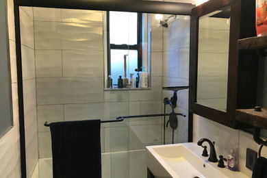 Small minimalist 3/4 white tile and porcelain tile ceramic tile and multicolored floor bathroom photo in New York with furniture-like cabinets, black cabinets, a two-piece toilet, white walls, a trough sink, solid surface countertops and white countertops