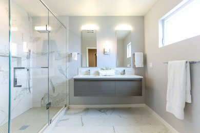 Large trendy master multicolored tile and porcelain tile marble floor and gray floor alcove shower photo in San Francisco with flat-panel cabinets, gray cabinets, quartz countertops, gray walls, an integrated sink, a hinged shower door and white countertops