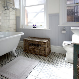 Inspiration för ett mellanstort lantligt badrum, med ett fristående handfat, möbel-liknande, skåp i slitet trä, träbänkskiva, ett badkar med tassar, en dusch/badkar-kombination, beige kakel och cementkakel