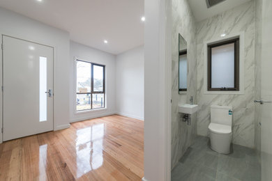 Réalisation d'une salle de bain design avec des portes de placard blanches, WC à poser, un carrelage multicolore, des carreaux de porcelaine, un mur blanc, un sol en carrelage de céramique, un lavabo suspendu, un sol gris et un plan de toilette blanc.