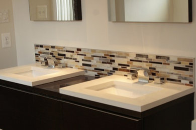 Bathroom - large contemporary master multicolored tile and glass tile laminate floor and beige floor bathroom idea in Baltimore with flat-panel cabinets, black cabinets, beige walls, an undermount sink, solid surface countertops and a two-piece toilet