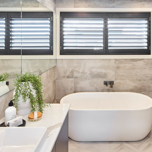 This is an example of a mid-sized contemporary master bathroom in Other with flat-panel cabinets, dark wood cabinets, a freestanding tub, a corner shower, gray tile, porcelain tile, a vessel sink, grey floor, a hinged shower door, white benchtops and a built-in vanity.