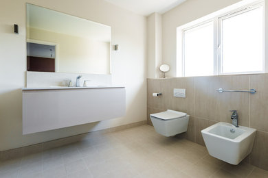 Inredning av ett modernt mellanstort en-suite badrum, med släta luckor, beige skåp, en dusch i en alkov, en vägghängd toalettstol, beige kakel, porslinskakel, beige väggar, klinkergolv i porslin och ett väggmonterat handfat
