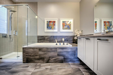 This is an example of a large traditional ensuite bathroom in Ottawa with recessed-panel cabinets, beige cabinets, a built-in bath, an alcove shower, a two-piece toilet, porcelain tiles, beige walls, ceramic flooring, a built-in sink, marble worktops, beige tiles, brown floors and a hinged door.