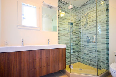 Example of a mid-sized trendy 3/4 porcelain tile and beige floor corner shower design in San Francisco with flat-panel cabinets, medium tone wood cabinets, a two-piece toilet, white walls, an integrated sink, quartz countertops, a hinged shower door and white countertops