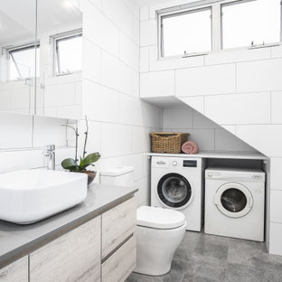 Design ideas for a contemporary bathroom in Sydney with flat-panel cabinets, light wood cabinets, an alcove shower, white tile, a vessel sink, grey floor, a hinged shower door, grey benchtops, a single vanity, a floating vanity and a laundry.