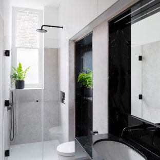 Medium sized contemporary shower room bathroom in London with an alcove shower, a wall mounted toilet, grey tiles, ceramic tiles, ceramic flooring, a submerged sink, granite worktops, a hinged door, black worktops, flat-panel cabinets, black cabinets and grey floors.