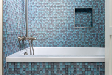 Modern inredning av ett litet badrum med dusch, med ett badkar i en alkov, en dusch i en alkov, blå kakel, glaskakel, vita väggar, klinkergolv i porslin och flerfärgat golv