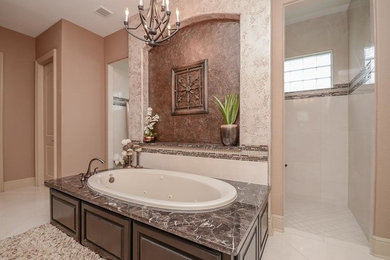 Inspiration for a large mediterranean master white tile and marble tile marble floor and white floor bathroom remodel in Houston with raised-panel cabinets, dark wood cabinets, a hot tub, a one-piece toilet, beige walls, an undermount sink and marble countertops