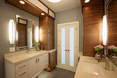 Exemple d'une salle de bain principale tendance de taille moyenne avec un placard à porte plane, des portes de placard blanches, une baignoire indépendante, une douche d'angle, WC séparés, un carrelage blanc, un mur gris, un sol en carrelage de porcelaine, un lavabo encastré, un plan de toilette en surface solide et des carreaux de céramique.