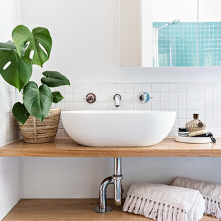 This is an example of a beach style bathroom in Wollongong with open cabinets, medium wood cabinets, blue tile, mosaic tile, white walls, a vessel sink, wood benchtops and brown benchtops.