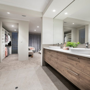 This is an example of a large contemporary master bathroom in Perth with flat-panel cabinets, medium wood cabinets, a freestanding tub, gray tile, white walls, porcelain floors, a vessel sink, grey floor and white benchtops.