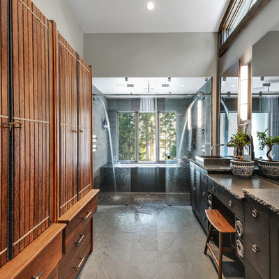 Example of a large mountain style master gray tile and stone tile ceramic tile and gray floor bathroom design in Other with furniture-like cabinets, brown cabinets, an undermount tub, a one-piece toilet, gray walls, a vessel sink, granite countertops and gray countertops
