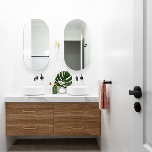 This is an example of a mid-sized beach style master bathroom in Sydney with shaker cabinets, white tile, porcelain tile, porcelain floors, a vessel sink, marble benchtops, grey floor, white benchtops, a double vanity, a floating vanity and medium wood cabinets.