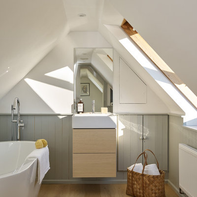 Freestanding bathtub - mid-sized scandinavian kids' light wood floor and brown floor freestanding bathtub idea in Hampshire with flat-panel cabinets, light wood cabinets, gray walls and a console sink