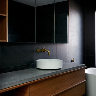 Photo of a contemporary bathroom in Canberra - Queanbeyan with flat-panel cabinets, medium wood cabinets, black walls, a vessel sink, concrete benchtops, black floor and grey benchtops.