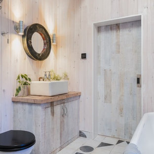 Design ideas for a rustic shower room bathroom in Cornwall with light wood cabinets, a freestanding bath, a two-piece toilet, beige walls, ceramic flooring, a vessel sink, wooden worktops, multi-coloured floors, flat-panel cabinets and brown worktops.