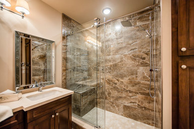 Inspiration for a mid-sized transitional master brown tile and porcelain tile porcelain tile double shower remodel in Toronto with furniture-like cabinets, medium tone wood cabinets, a two-piece toilet, beige walls, an undermount sink and limestone countertops
