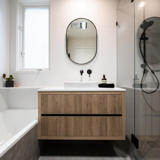 Design ideas for a mid-sized contemporary master bathroom in Melbourne with furniture-like cabinets, medium wood cabinets, a corner shower, white tile, ceramic tile, white walls, porcelain floors, a vessel sink, engineered quartz benchtops, brown floor, a hinged shower door and white benchtops.