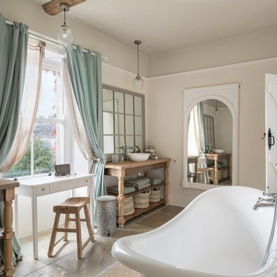 Inspiration for a shabby-chic style brown floor freestanding bathtub remodel in Gloucestershire with open cabinets, beige walls, a vessel sink, wood countertops and brown countertops