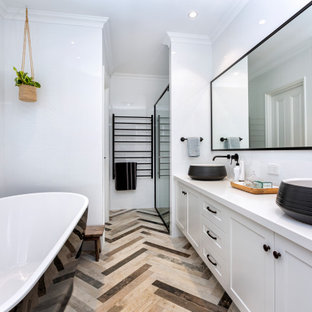 Photo of a mid-sized beach style master bathroom in Perth with shaker cabinets, white cabinets, a freestanding tub, a corner shower, a two-piece toilet, white tile, ceramic tile, white walls, mosaic tile floors, a vessel sink, engineered quartz benchtops, brown floor, a hinged shower door, white benchtops, a double vanity and a built-in vanity.