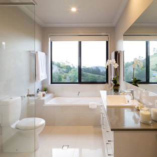 This is an example of a contemporary master bathroom in Brisbane with flat-panel cabinets, white cabinets, an alcove tub, a corner shower, a one-piece toilet, beige tile, beige walls, a drop-in sink, beige floor, an open shower and brown benchtops.