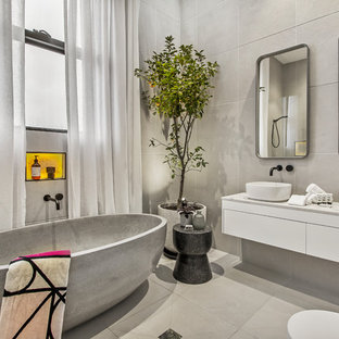 Contemporary bathroom in Melbourne with flat-panel cabinets, white cabinets, a freestanding tub, grey walls, a vessel sink, grey floor and white benchtops.