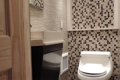 ニューヨークにある高級な小さなモダンスタイルのおしゃれな浴室 (ベッセル式洗面器、フラットパネル扉のキャビネット、濃色木目調キャビネット、クオーツストーンの洗面台、ベージュのタイル、ガラスタイル、磁器タイルの床、一体型トイレ	、グレーの壁) の写真