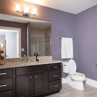 Esempio di una stanza da bagno con doccia american style con lavabo sottopiano, ante con riquadro incassato, ante in legno bruno, top in granito, vasca ad alcova, doccia alcova, WC a due pezzi, piastrelle grigie, piastrelle in gres porcellanato, pareti viola e pavimento in gres porcellanato