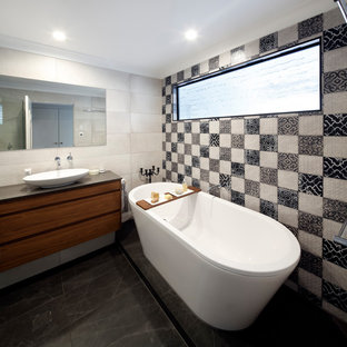Design ideas for a mid-sized mediterranean master bathroom in Sydney with flat-panel cabinets, medium wood cabinets, a freestanding tub, beige tile, black and white tile, cement tile, a vessel sink, black floor, brown benchtops, a corner shower, a one-piece toilet, grey walls, porcelain floors, engineered quartz benchtops and a hinged shower door.
