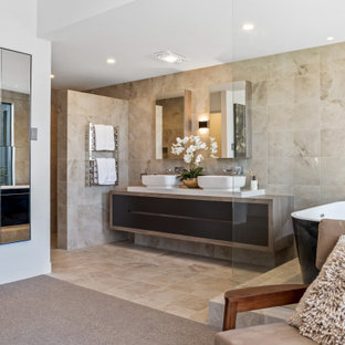 Photo of a contemporary master bathroom in Perth with flat-panel cabinets, black cabinets, a freestanding tub, beige tile, a vessel sink, wood benchtops, beige floor and brown benchtops.