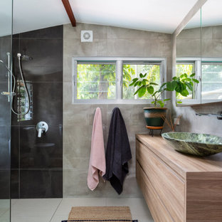 This is an example of a contemporary bathroom in Sunshine Coast with flat-panel cabinets, medium wood cabinets, a curbless shower, gray tile, a vessel sink, wood benchtops, beige floor, an open shower, brown benchtops, a single vanity, a floating vanity and vaulted.