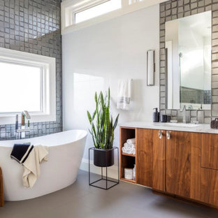 Inspiration for a contemporary gray tile gray floor and double-sink freestanding bathtub remodel in Seattle with flat-panel cabinets, medium tone wood cabinets, white walls, an undermount sink, white countertops and a built-in vanity