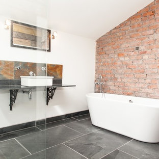 Inspiration for a mid-sized industrial bathroom in Other with a freestanding tub, a one-piece toilet, black tile, white walls, slate floors, a vessel sink, an open shower and slate.