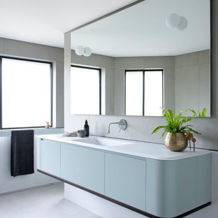 Large contemporary bathroom in Sydney with blue cabinets, mosaic tile, porcelain floors, an integrated sink, solid surface benchtops, grey floor, white benchtops, flat-panel cabinets and white tile.