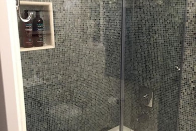 Cette photo montre une salle d'eau tendance de taille moyenne avec une baignoire en alcôve, un combiné douche/baignoire, un carrelage noir, un carrelage gris et mosaïque.