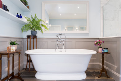 This is an example of a large classic ensuite bathroom in Other with recessed-panel cabinets, white cabinets, a freestanding bath, a built-in shower, a one-piece toilet, blue tiles, blue walls, porcelain flooring, a built-in sink, marble worktops, brown floors, a hinged door and white worktops.
