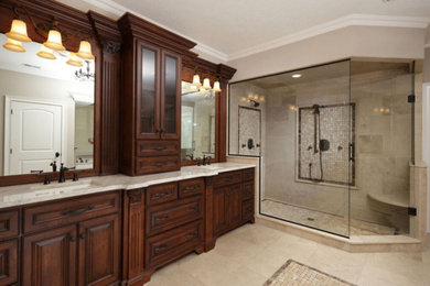 Bathroom - large transitional master limestone tile limestone floor and beige floor bathroom idea in Other with raised-panel cabinets, dark wood cabinets, a one-piece toilet, beige walls, an undermount sink, granite countertops and a hinged shower door